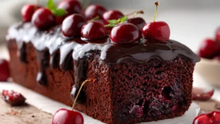 Moist chocolate cherry cake with fudgy chocolate glaze and cherries on top.