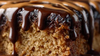 Peanut butter chocolate sheet cake with glossy icing sliced on a wooden table.